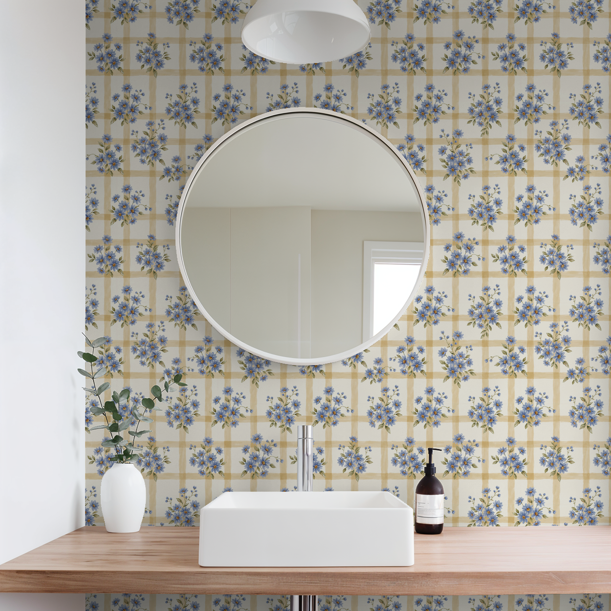 Bathroom with blue floral and gold grid wallpaper, round mirror, white sink.