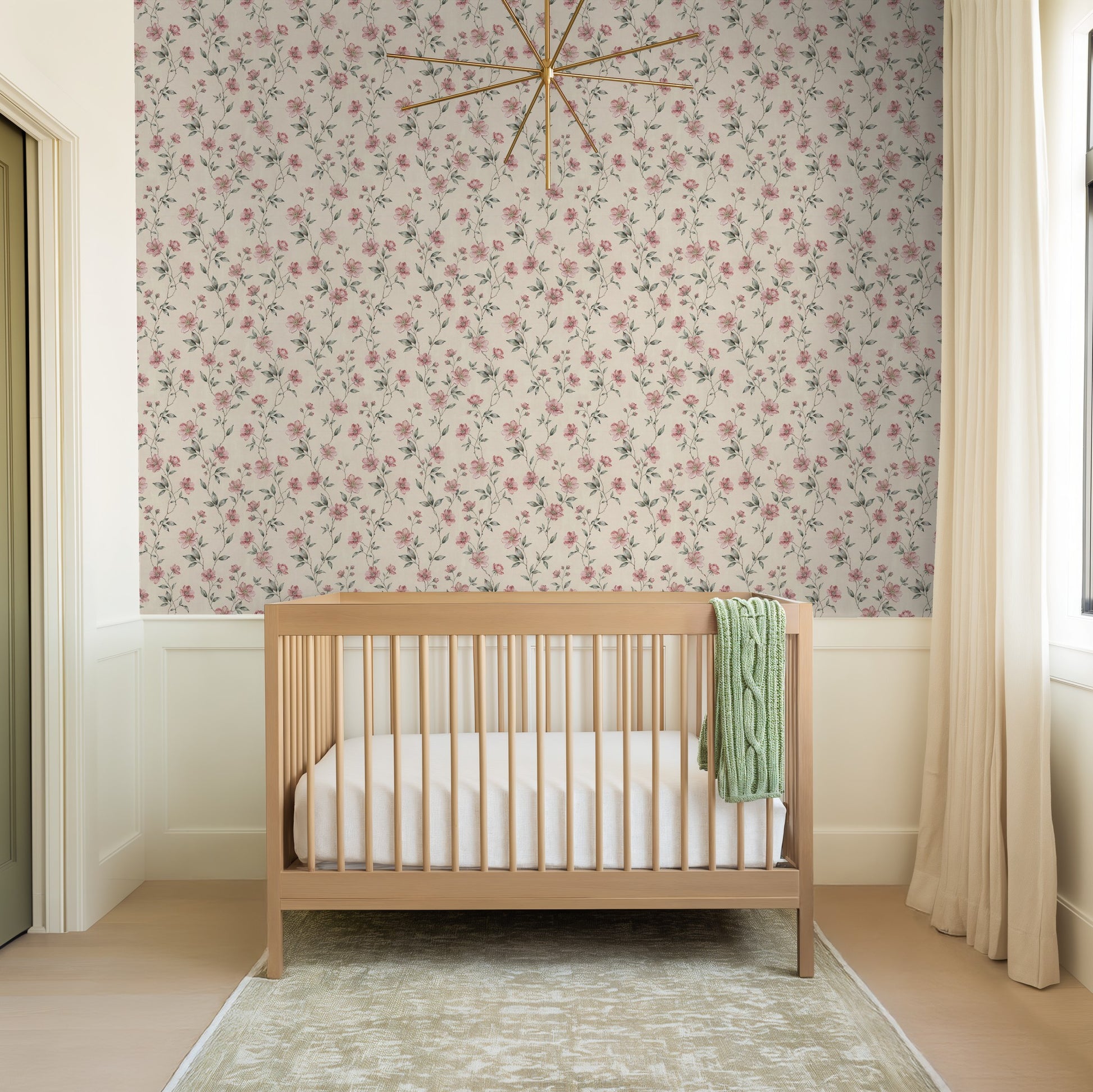 Blush floral wallpaper in nursery with wooden crib and soft lighting.