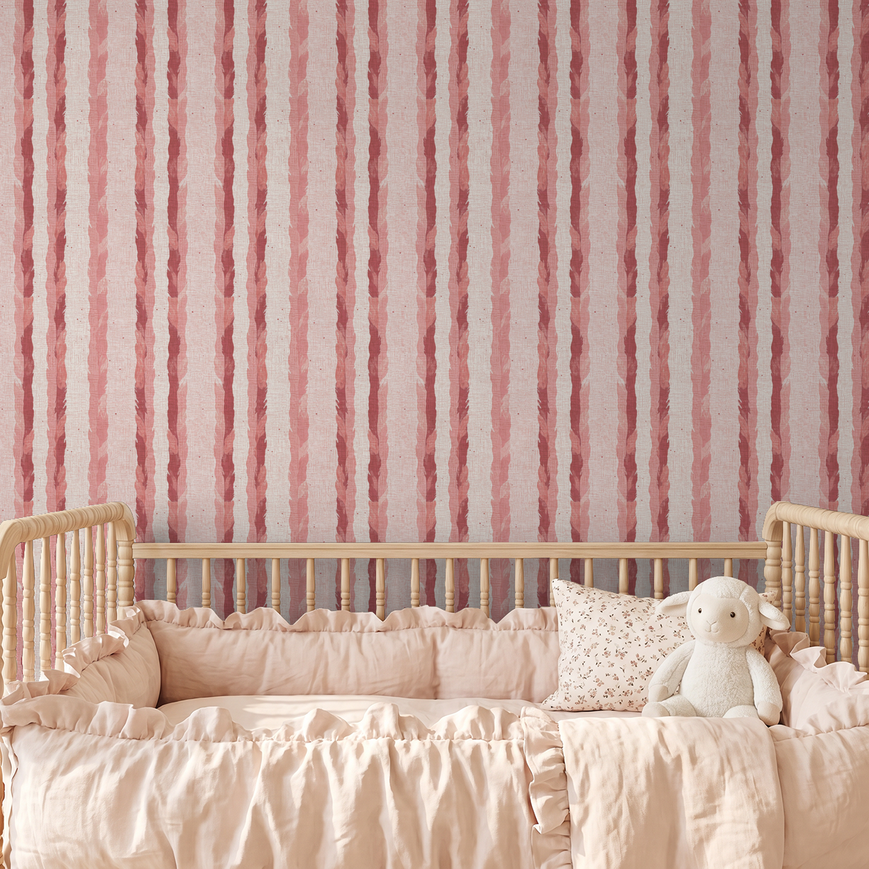 Blush and rose feather stripe wallpaper in a cozy nursery with crib and plush toy.