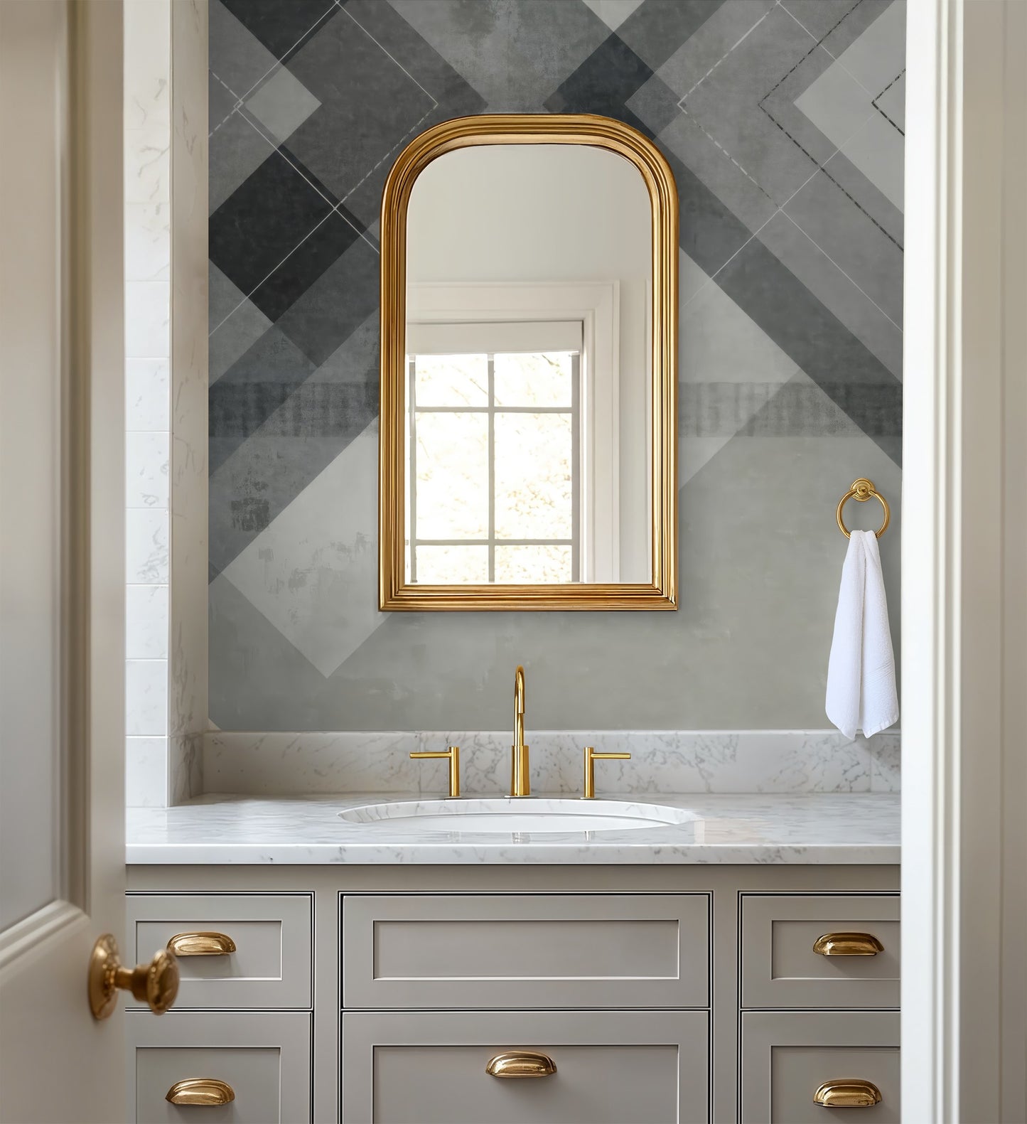 Chevron geometric grey and white wallpaper in modern bathroom with gold accents.
