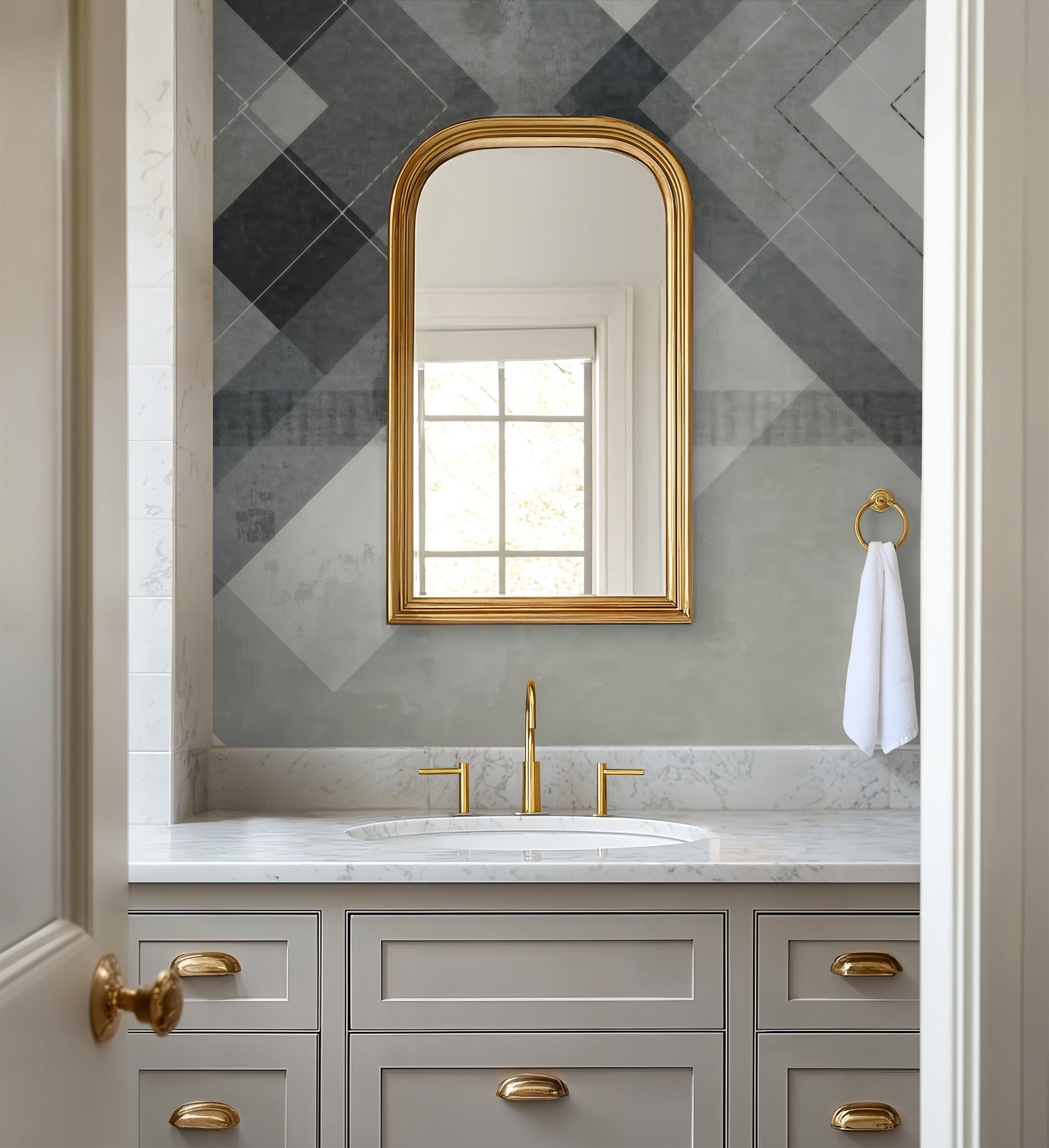 Chevron geometric grey and white wallpaper in modern bathroom with gold accents.