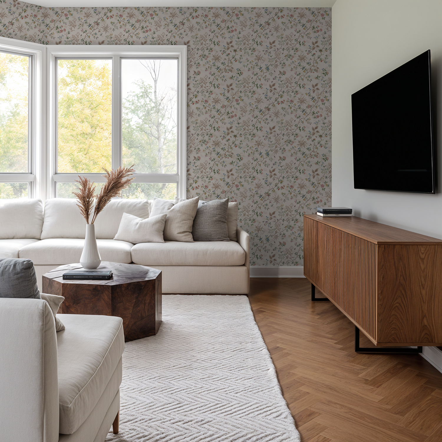 Floral wallpaper with pastel hues in a modern living room with white sofa and wooden furniture.
