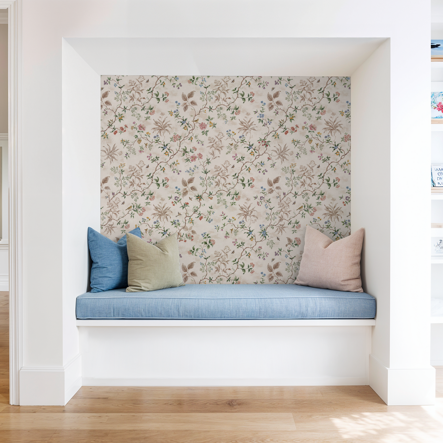 Floral botanical wallpaper with pastel vines in a cozy nook with blue cushions.