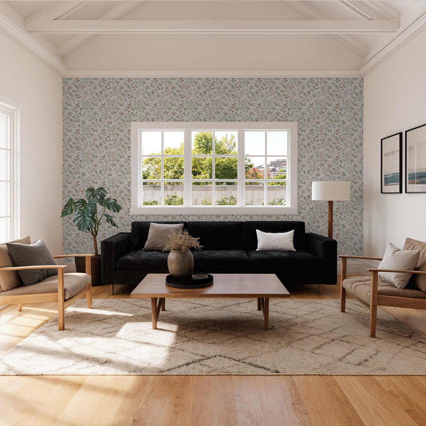 Living room with Garden Gala floral wallpaper in pastel tones, black sofa, wooden furniture.