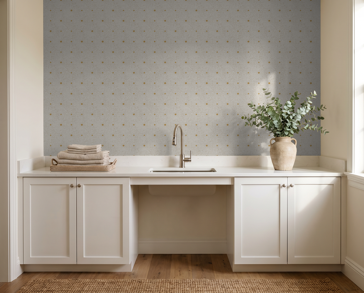 Geometric cream and gold wallpaper in a modern laundry room with white cabinets and plants.