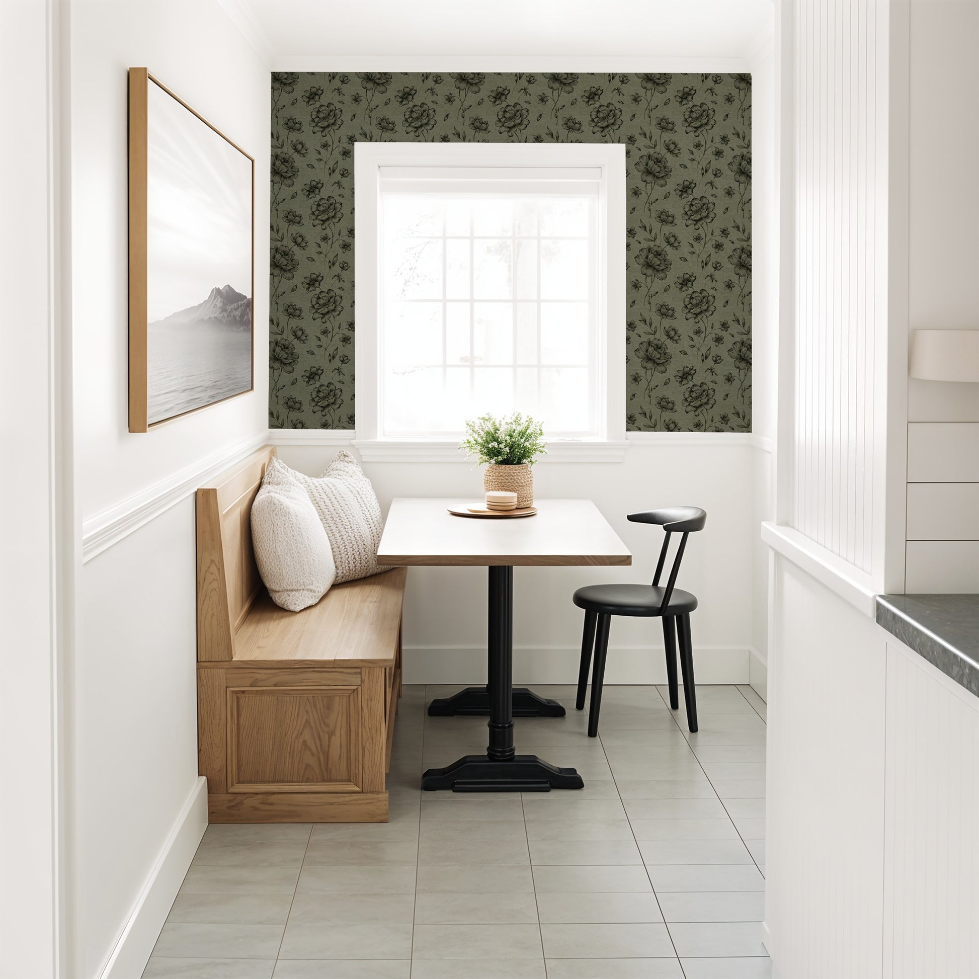 Olive floral wallpaper with charcoal motifs in a cozy dining nook with wood seating.